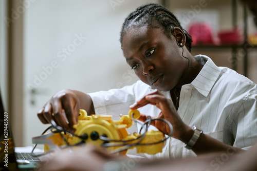 African American young woman engineer assembling robotics prototype in laboratory. Visual represents STEM education, technology innovation for engineering campaign