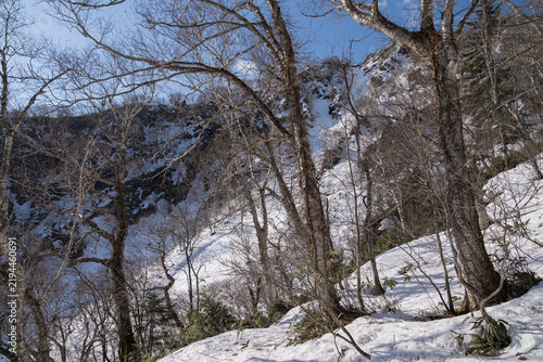 Late snow lingering on a steep forest slope above a caldera lake