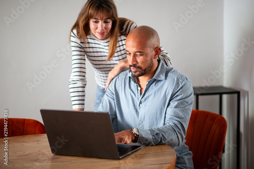 Couple reviewing online information together on laptop at home