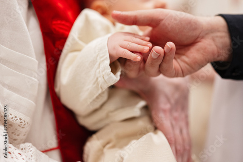 Foto Parent and priest holding baby hand during christening baptism ceremony in churc