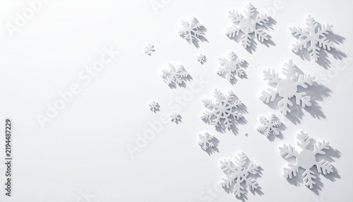 Delicate decorative snowflake ornaments arranged on a bright white winter background with soft shadows and open copy space for Christmas holiday cards, banners, invitations and seasonal design