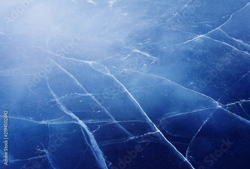Frosted ice surface with intricate crack patterns under natural light