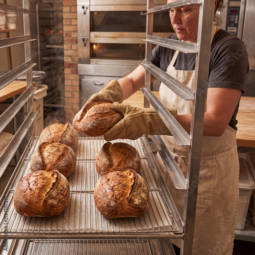 Baker arranging bread loaves on commercial cooling rack
