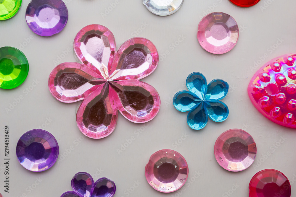 Obraz premium Colorful Flower Shaped Rhinestones and Plastic Gems Craft Accessories on White Background