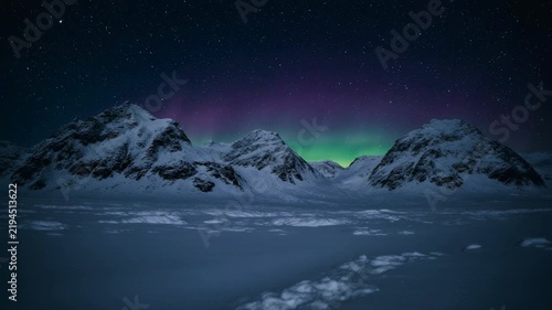 Northern Lights dancing above snowy mountains during a cold winter night