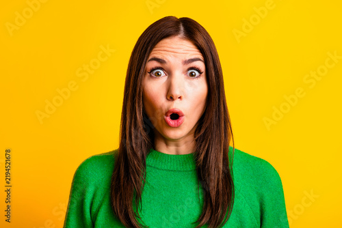Картината върху платно Surprised young woman portrait in green sweater on bright yellow background show