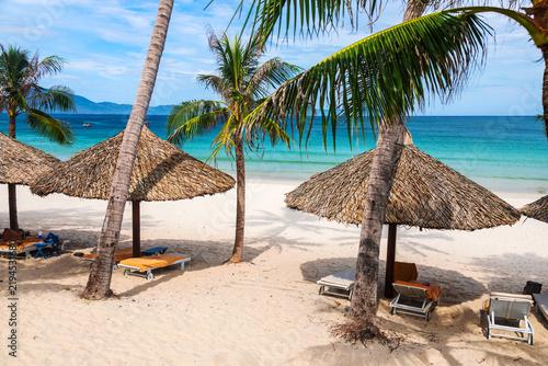 Doc Let beach in Vietnam with coconut palms, thatched umbrellas, sun loungers, and calm turquoise sea