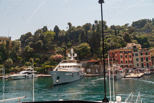 Obraz na płótnie Waterfront view of Portofino harbor with luxury yachts, colorful Italian buildings and lush Mediterranean vegetation on a bright summer day in Liguria, Italy