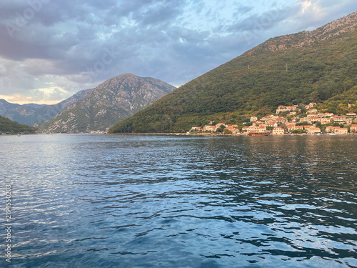 Scenic view of a coastal village nestled at the base of green mountains along a bay