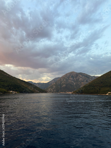Scenic view of a bay surrounded by steep mountains under a cloudy twilight sky