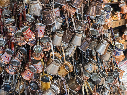 Large variety selection of Turkish coffee pots hanging on display at local bazaar market stall creating abstract background wallpaper