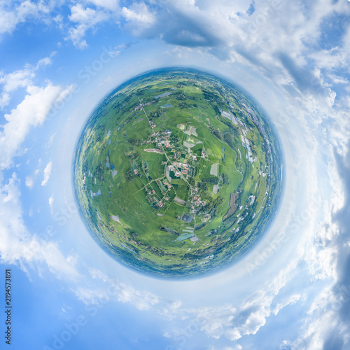 Fotografie A tiny planet styled panoramic view showing rural fields, settlements and blue sky, depicting a natural landscape