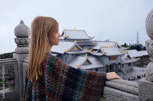 Obraz na płótnie Young woman with long blonde hair wearing a colorful patterned shawl stands on a
