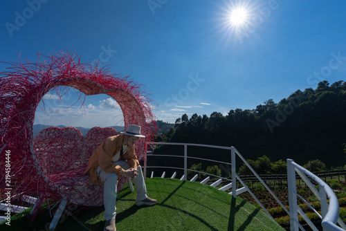 Obraz na płótnie A tourist sits inside a large pink heart-shaped frame at a scenic mountain viewpoint in Mon Jam, Chiang Mai, Thailand