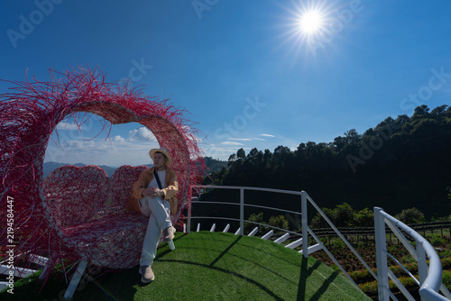 Fotografie A tourist sits inside a large pink heart-shaped frame at a scenic mountain viewpoint in Mon Jam, Chiang Mai, Thailand