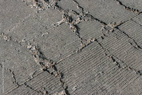 A close-up of cracks on a concrete road surface, revealing damage, potholes, and signs of wear; ideal for illustrating concepts such as infrastructure damage, maintenance, transport safety, and urban 