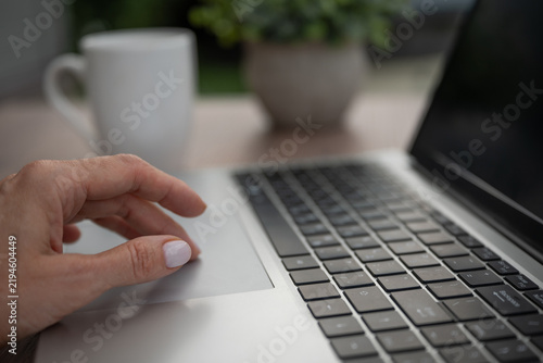 Fotografie Close up of female hand using laptop touchpad at home workspace