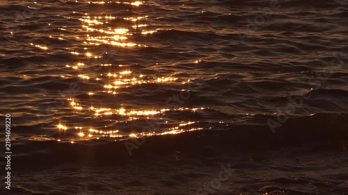 Sea water waves moving under golden sunset light, marine sunset texture, dramatic evening scene.