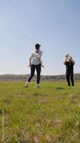 Happy young caucasian couple playing volleyball in a green field on a sunny day, enjoying an active outdoor lifestyle and spending quality time together during their summer vacation