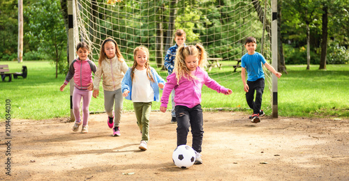 Group of young childs playing soccer ball outdoors in park