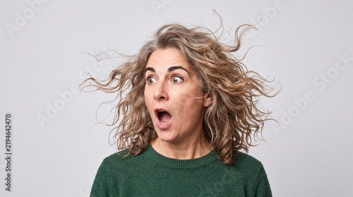Shocked funny middle aged woman with messy hair looking surprised