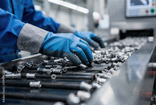 Worker's Hands Sorting Small Metal Parts on a Production Line