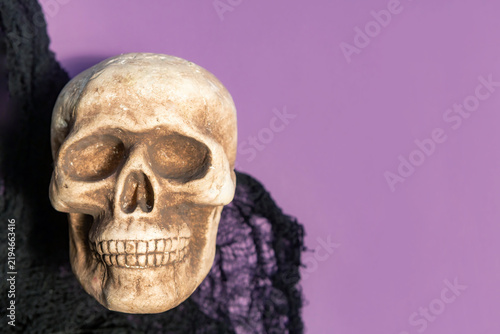 Foto Halloween skull decoration draped in black fabric against a purple background wi