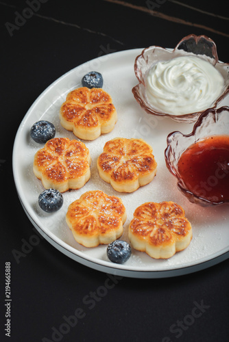 Cottage cheese pancakes, syrniki, curd fritters decorated with strawberry and raspberry served on a white plate. Homemade breakfast concept