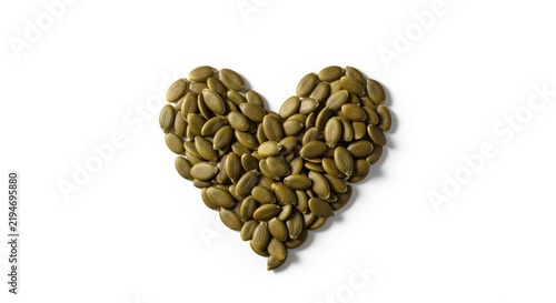 Pumpkin seeds arranged in heart shape on white background, healthy food and nutrition concept