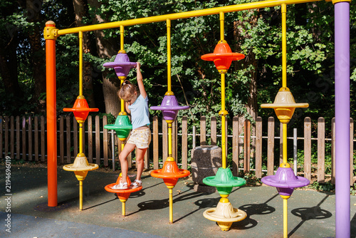 Happy Girl Playing on Colorful Playground Equipment in Sunny Park, Active Childhood and Outdoor Fun