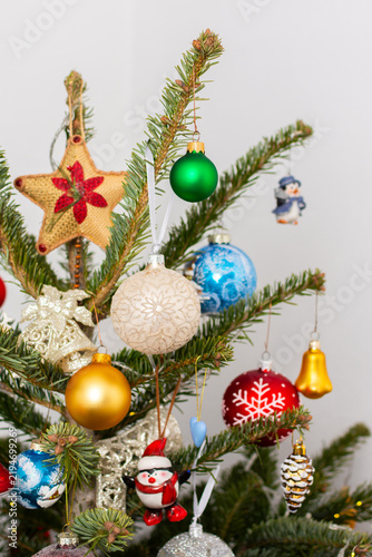 A Christmas tree stands with many colorful ornaments hanging from its branches. Each ornament shows different shapes and colors, celebrating the festive season and bringing joy to the home