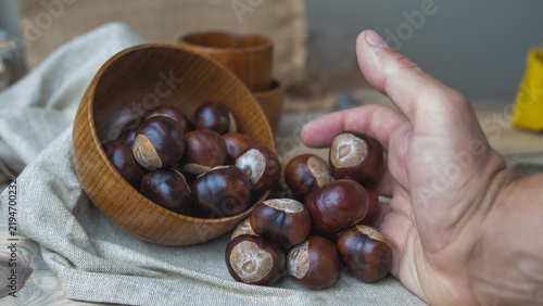Foto castañas en otoño sobre la mesa y con una mano apartando algunas
