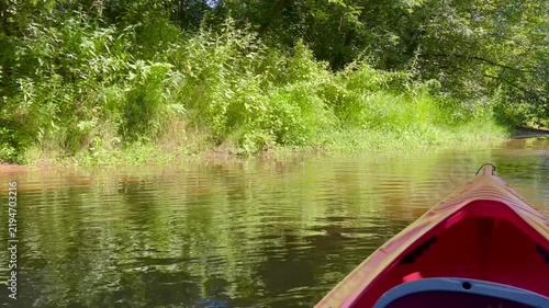 POV ride in a red kayak on a peaceful river surrounded by lush green trees and summer vegetation, scenic outdoor paddling adventure in 4K.