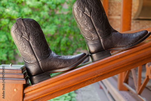 Obraz na plátně pair of leather boots standing against background of green leaves