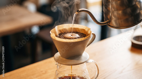 Pour over coffee brewing process with hot water being poured into a ceramic dripper