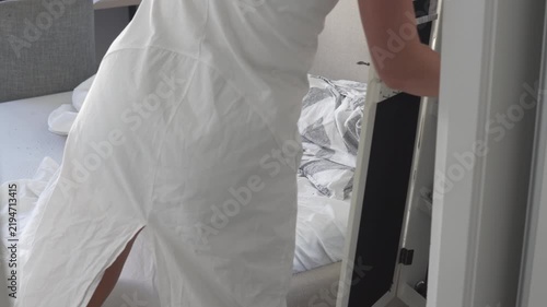 Woman removing used and dirty bed linen from a bed at home. Changing sheets and stripping the bed before washing and replacing the bedding