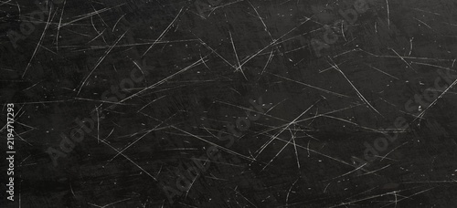 Dark grunge background texture featuring a heavily scratched black surface with white distress marks
