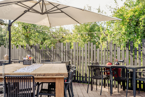 Outdoor dining terrace with wooden table, chairs and patio umbrella