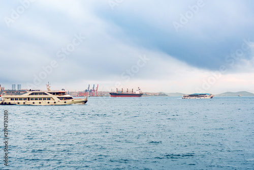 Boats and ships on the water near a city port during a cloudy day