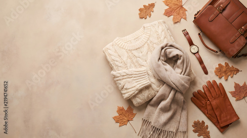 Knitted sweater and autumn accessories are neatly arranged on a neutral flat lay background.