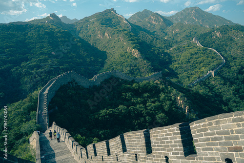 Obraz na płótnie Winding Great Wall of China snaking over forested mountain ridges under blue sky