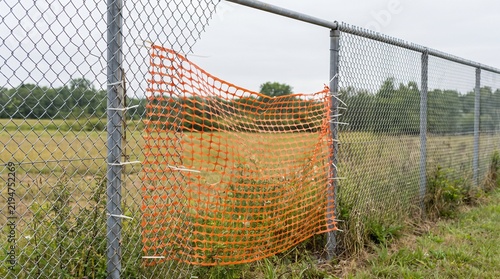 Orange Plastic Mesh Patching A Chain Link Fence as Weak Link Metaphor