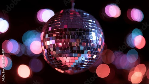 Disco ball slowly rotating surrounded by multicolored pink and purple bokeh lights, vibrant New Year party video for celebration, nightlife