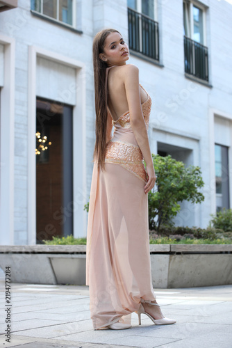 Elegant Young Woman In Sparkling Gold Evening Gown Posing Outdoors