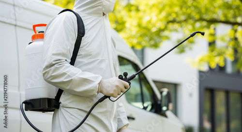 Professional exterminator in hazmat suit spraying chemicals outdoors perfect for industrial pest control services and toxic disinfection concepts