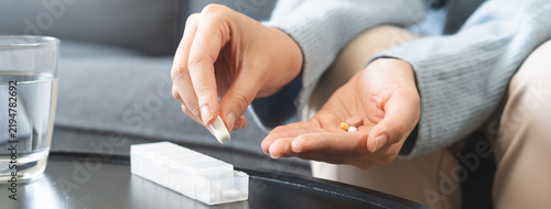 Obraz na plátne Sick asian young woman, girl holding tablet pill on hand pour capsule from medication box, painkiller medicine from stomach pain, headache, pain for treatment, take drug or vitamin, health care
