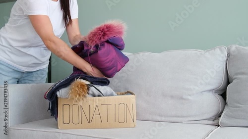 Donation box with winter clothes. The volunteer puts the different warm garment into a cardboard box.

