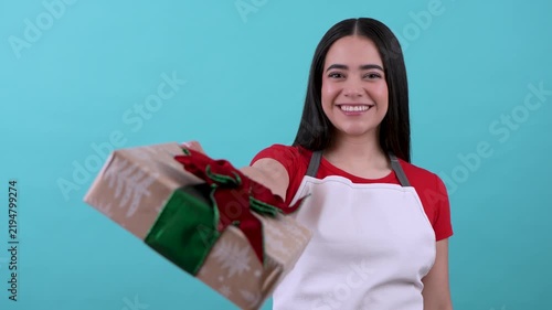 Cheerful latina shopkeeper offering a beautiful christmas gift