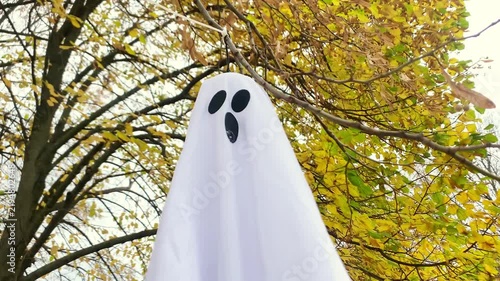 Spooky silhouette ghosts faces waving on wind on halloween forest background,autumn holidays,decoration and party concept.