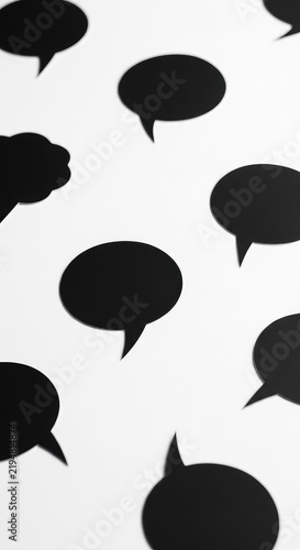 Multiple solid black comic style speech bubbles with sharp and rounded edges scattered across a plain white surface creating high contrast, isolated, presentation, collection